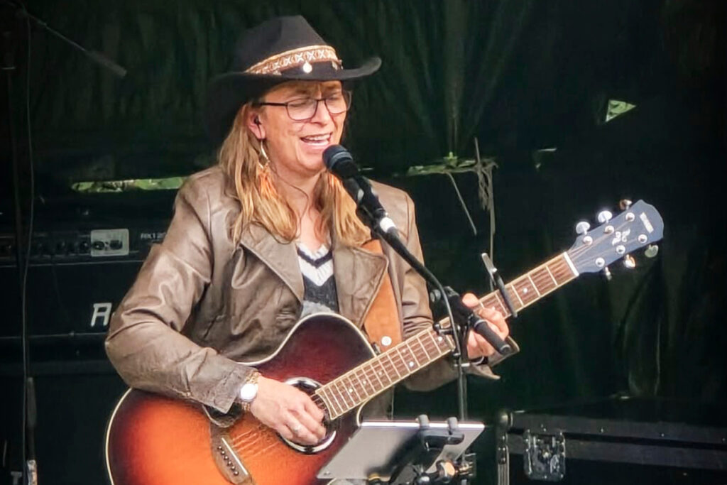 Dame som spiller på gitar med cowboyhatt